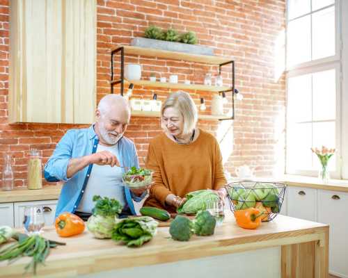 Couple senior préparant une salade ensemble dans une cuisine avec des légumes frais - Senior couple preparing a salad together in a kitchen with fresh vegetables