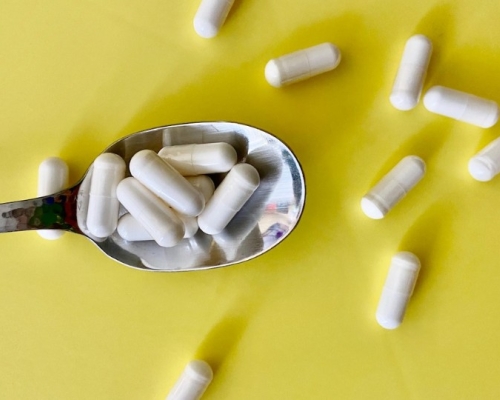 Supplements in a spoon on a yellow background