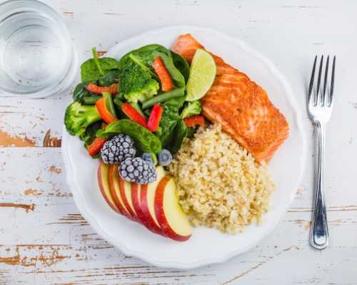 Plate with salmon, rice, salad and apple