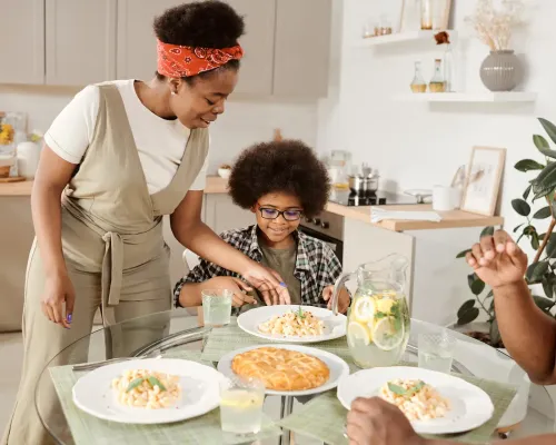 Famille souriante partageant un repas - Smiling family sharing a pasta meal