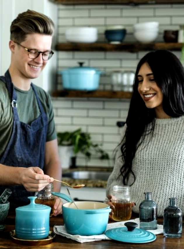 man and woman smiling as they cook