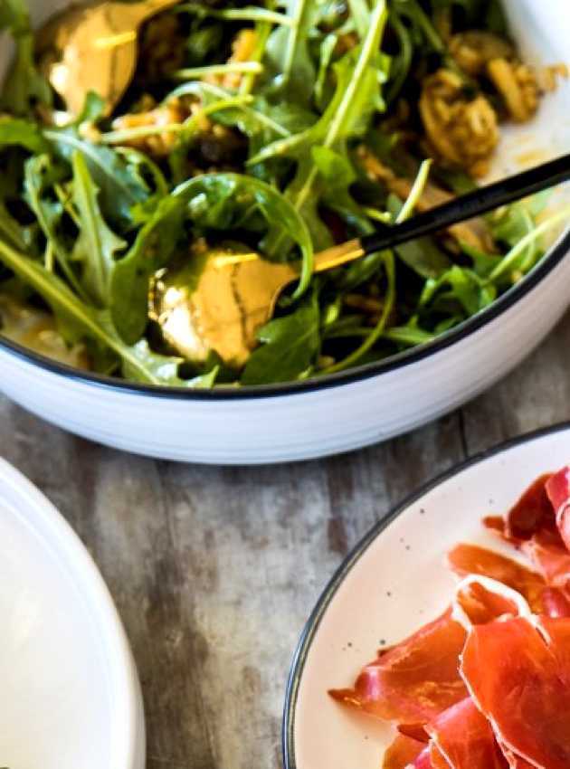 A plate of prosciutto and a plate of arugula