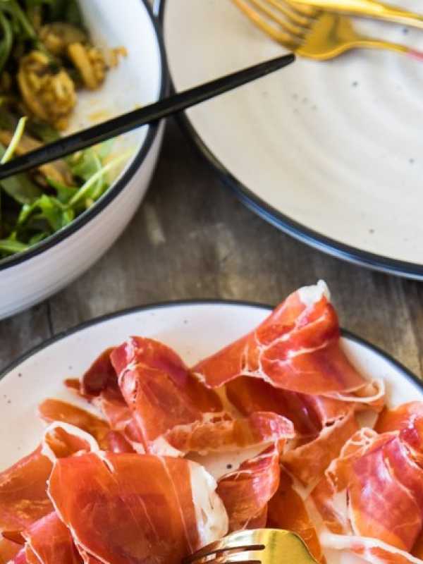 A plate of prosciutto and a plate of arugula