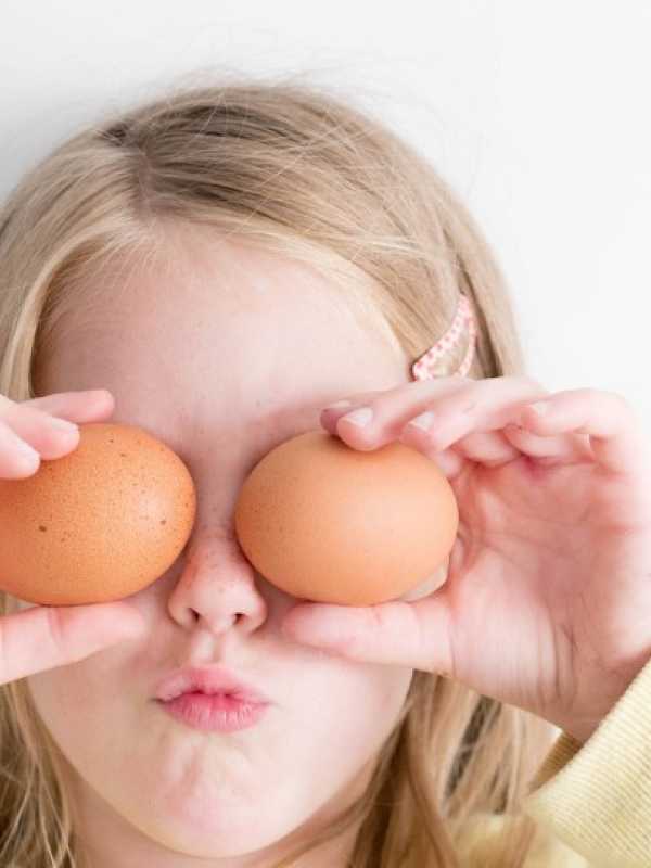 child hiding his eyes with eggs