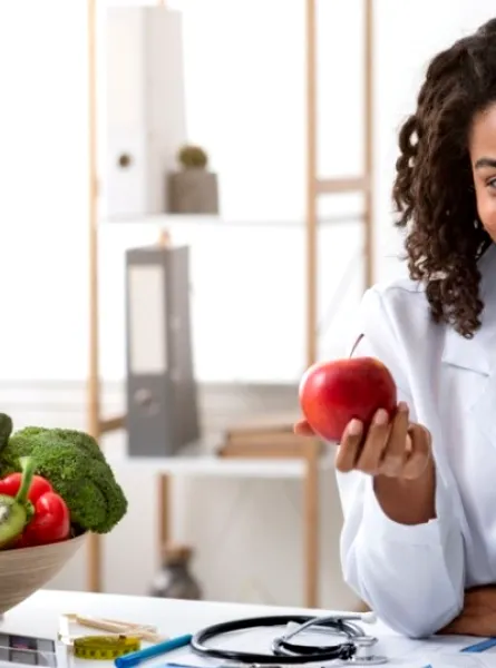 nutritionist-dietitian in her office presenting a fruit