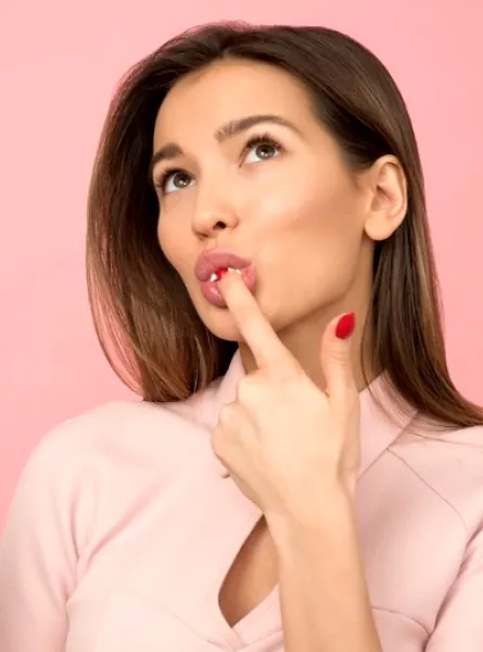 Woman eating a cake in front of a pink screen