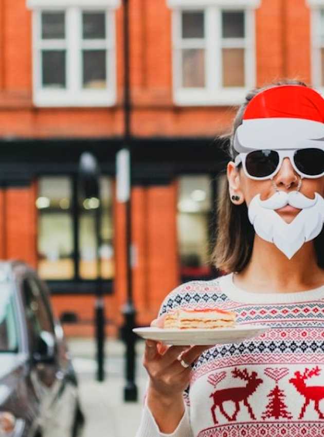 woman dressed as santa claus holding a glass of eggnog and a dessert