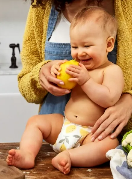 baby on the counter touching fruits