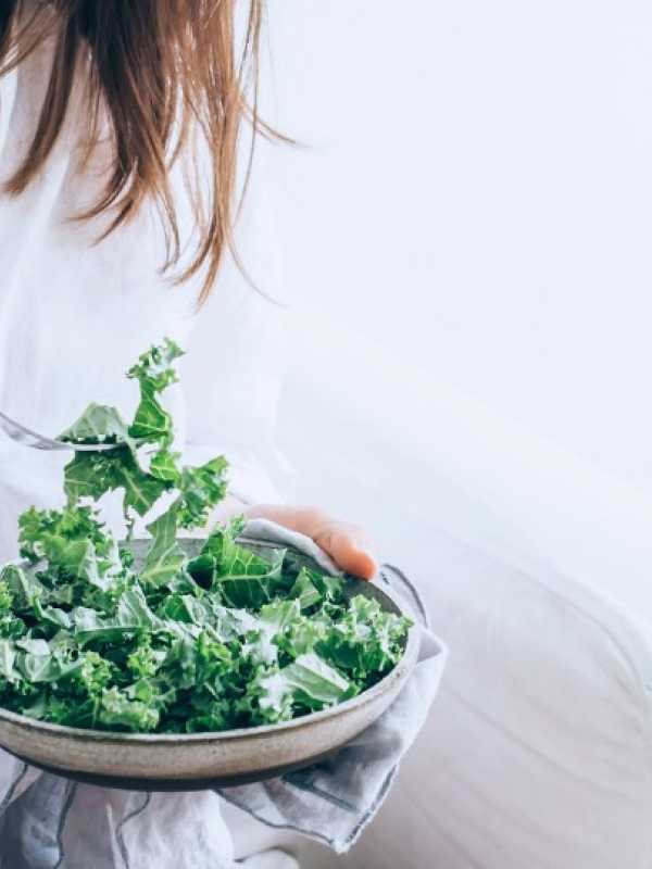 Girl dressed in white eating a kale salad
