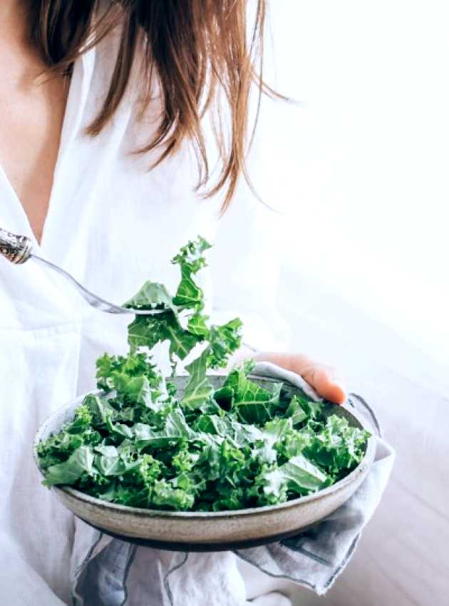 Girl dressed in white eating a kale salad