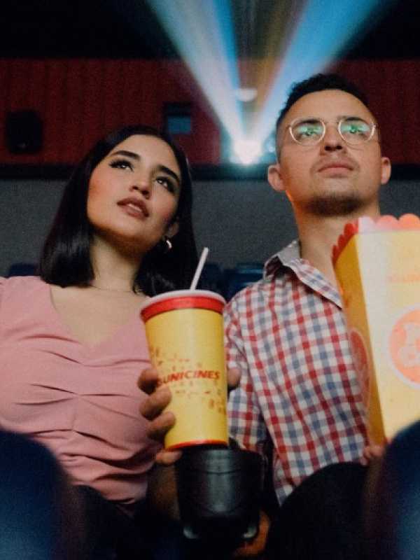 couple qui mange du popcorn avec des boissons gazeuses en écoutant un film au cinéma