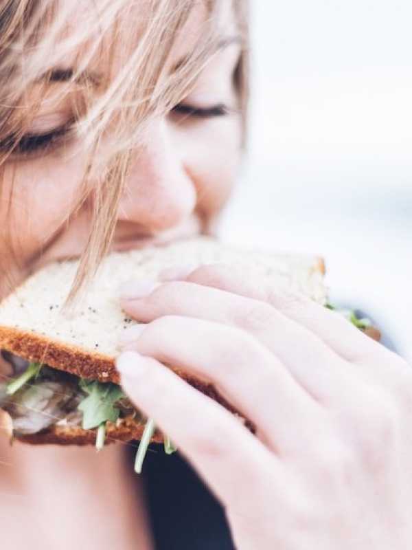 Girl eating a sandwich with wind blowing her hair