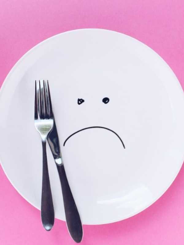 sad plate with a fork and a knife on a pink background