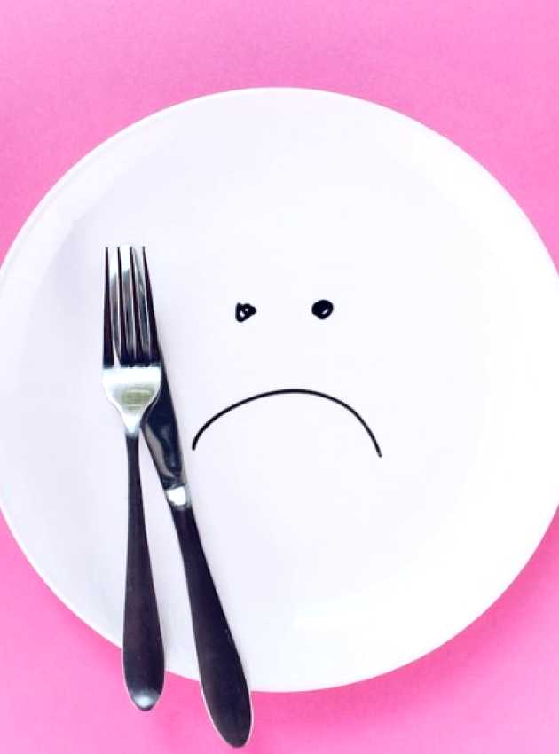 sad plate with a fork and a knife on a pink background