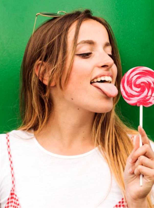 girl with a white t-shirt licking a candy, green background