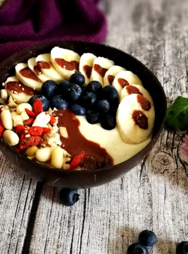 Smoothie or yogourt bowl on un wooden backsplash with a purple blanket