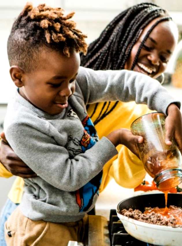 mother and son smiling and cooking