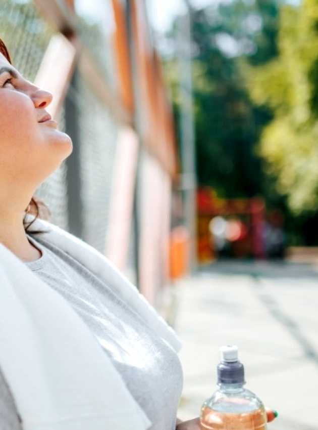 Woman taking a break after outdoor exercise, holding a water bottle, symbolizing a weight loss journey