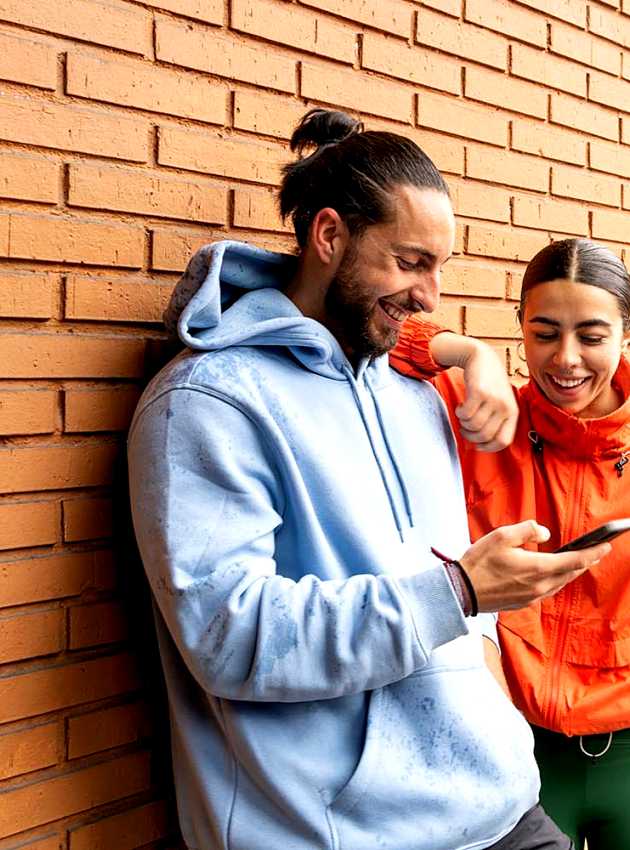 Deux amis souriants regardent un téléphone - Two smiling friends looking at a phone