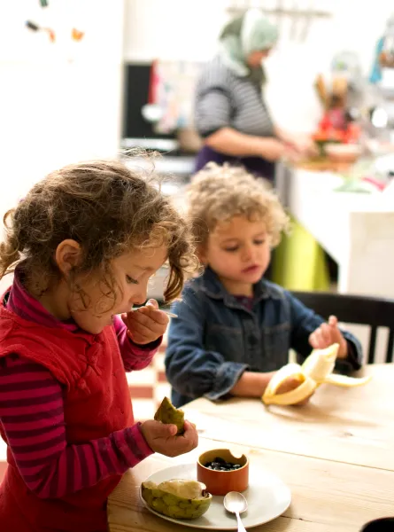 two little girls tasting fruit