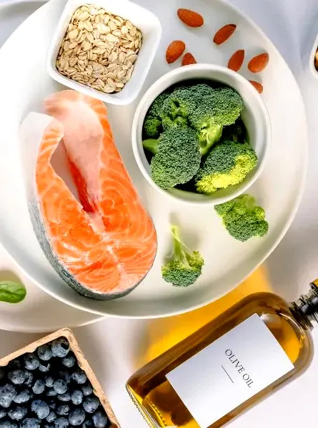un assortiment d'aliments comprenant du saumon, du brocoli, des noix, des myrtilles, des noix et de l'huile d'olive