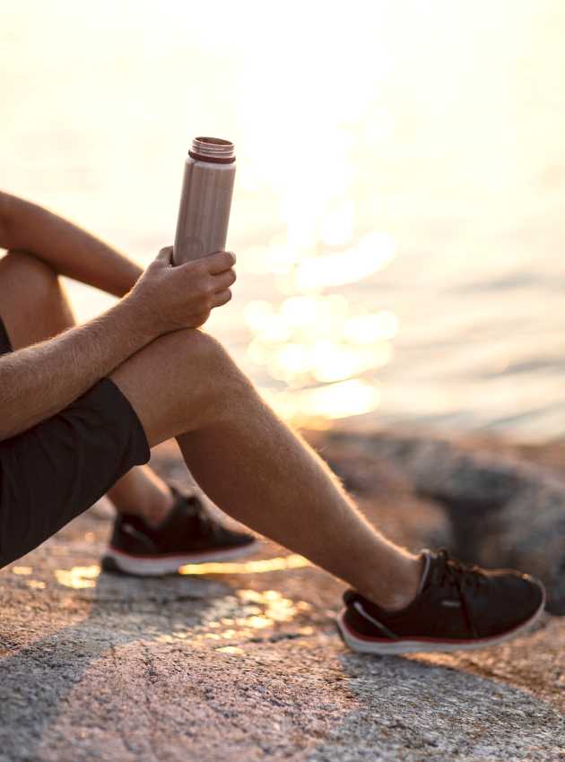 sportsman on the water's edge with his water bottle