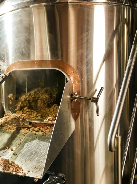man taking the spent grains out of the brewing system