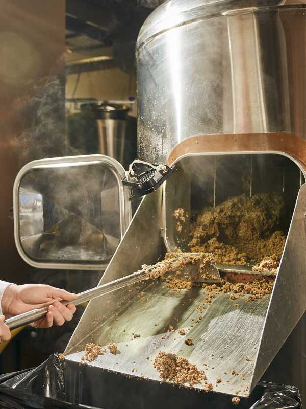man taking the spent grains out of the brewing system