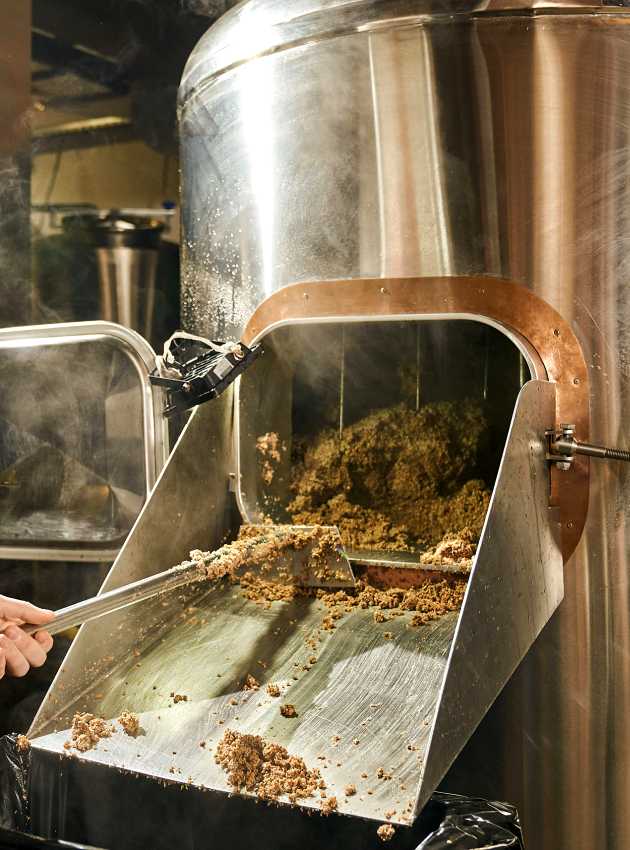 man taking the spent grains out of the brewing system