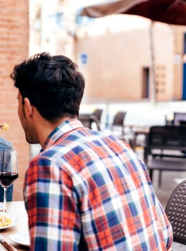 Group of friends enjoying a meal together at an outdoor restaurant, sharing laughs and conversation. The setting reflects a casual and joyful dining experience, highlighting the social benefits of eating out while maintaining healthy choices.