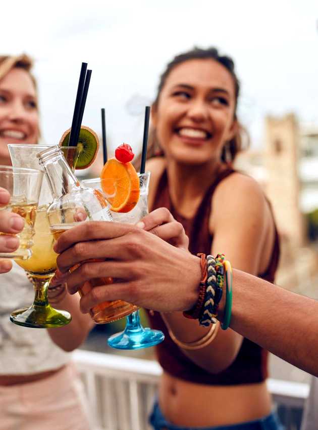 Des amis trinquent avec des cocktails lors d'une fête en plein air - Friends toasting with cocktails at an outdoor party