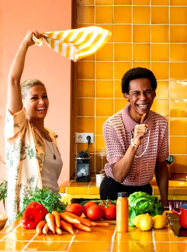 Trois amis souriants s’amusent ensemble dans une cuisine colorée - Three smiling friends have fun together in a colorful kitchen