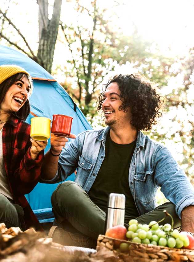 A happy family camping in the forest, drinking tea in front of their tent - Une famille heureuse campe dans la forêt, buvant du thé devant leur tente