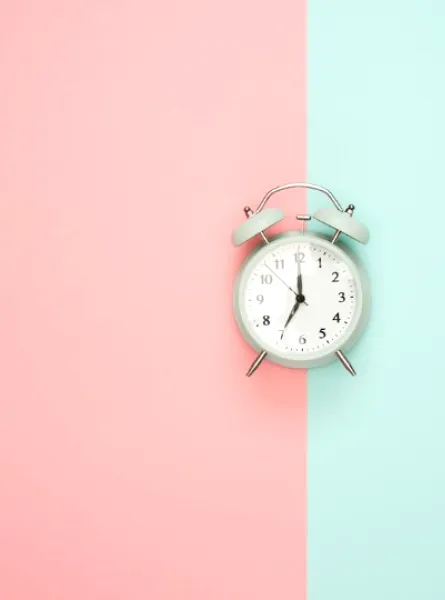 clock in the middle of a background pink and turquoise