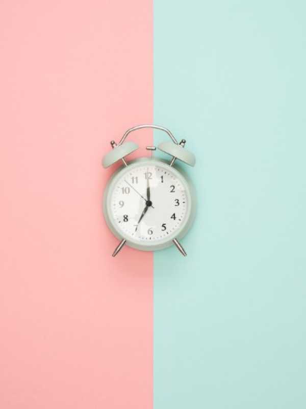 clock in the middle of a background pink and turquoise
