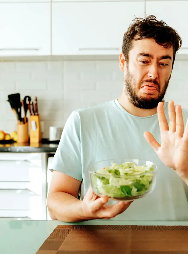 Homme faisant la grimace en tenant un bol de salade - Man grimacing while holding a bowl of salad