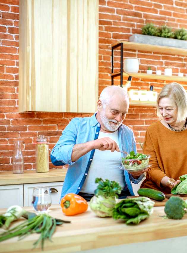 Couple senior préparant une salade ensemble dans une cuisine avec des légumes frais - Senior couple preparing a salad together in a kitchen with fresh vegetables