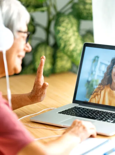 Older woman with headphones waving during a video call - Femme âgée avec des écouteurs faisant signe de la main pendant un appel vidéo