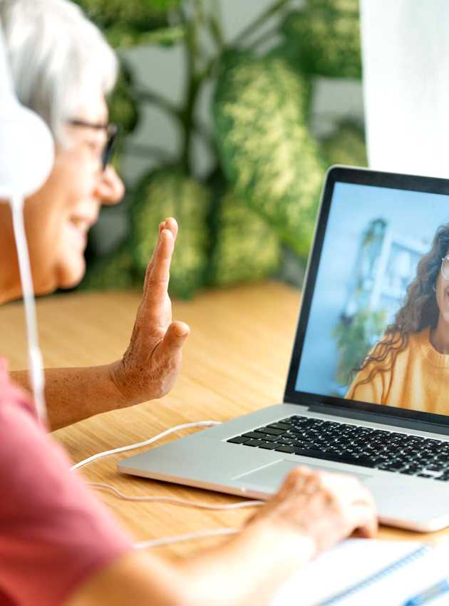 Older woman with headphones waving during a video call - Femme âgée avec des écouteurs faisant signe de la main pendant un appel vidéo