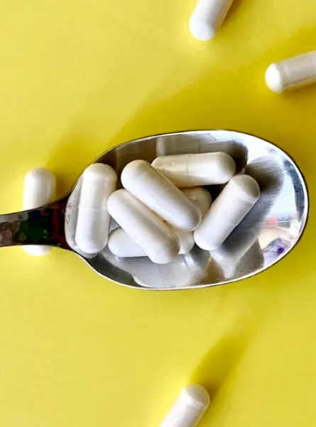 Supplements in a spoon on a yellow background